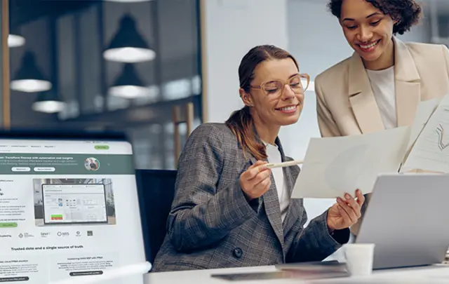 Twee finance professionals die samen rapporten bekijken, met Unit4 FP&amp;A-software op een laptopscherm op de voorgrond