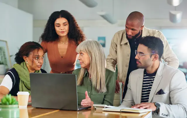 Cross-functional FP&amp;A team collaborating around a laptop to align financial and operational planning