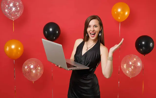 person celebrating with laptop and balloons