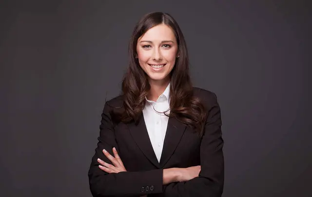 a smartly dressed woman smiling in front of a dark background