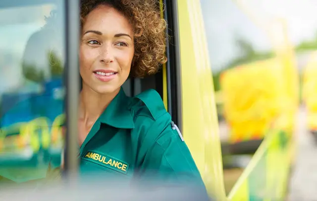 a woman in a paramedic uniform sitting in the front of an ambulance