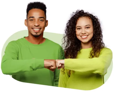 Two friends fist-bumping, both wearing bright green sweatshirts, smiling at the camera. 