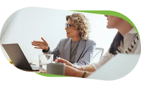 Two women engaged in a professional discussion at a light-colored table. 