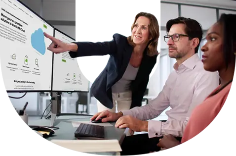 Three professionals collaborate in an office setting, with a woman pointing at a computer screen displaying a large blue cloud icon and text about cloud solutions. 