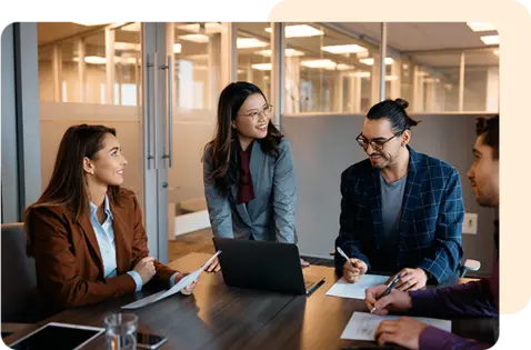 Four colleagues collaborate around a dark wooden table in a modern office. 