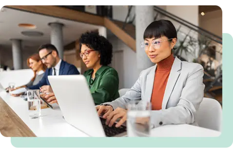 Professionals working on laptops during a collaborative business meeting in a modern office. 