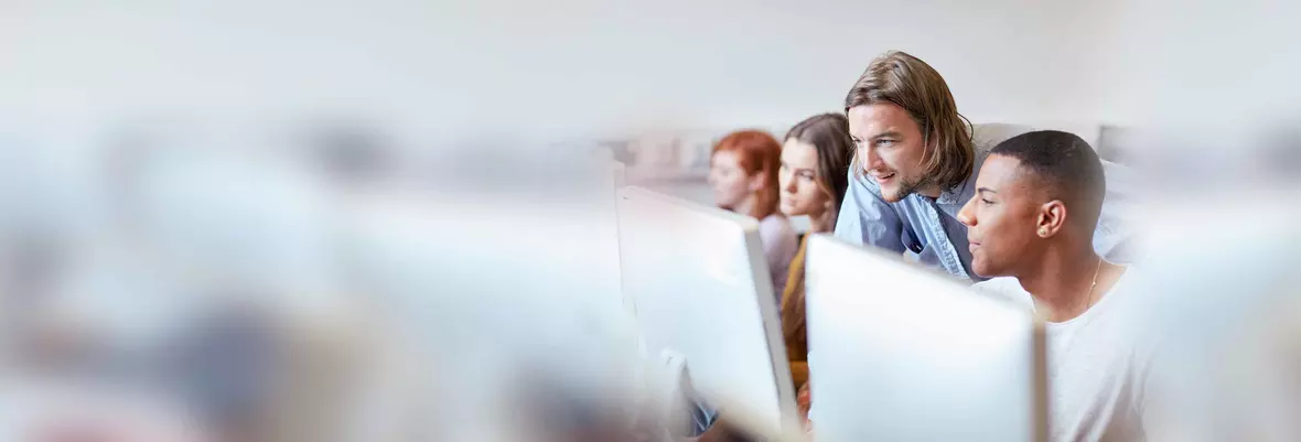 two young men focused on a pc monitor