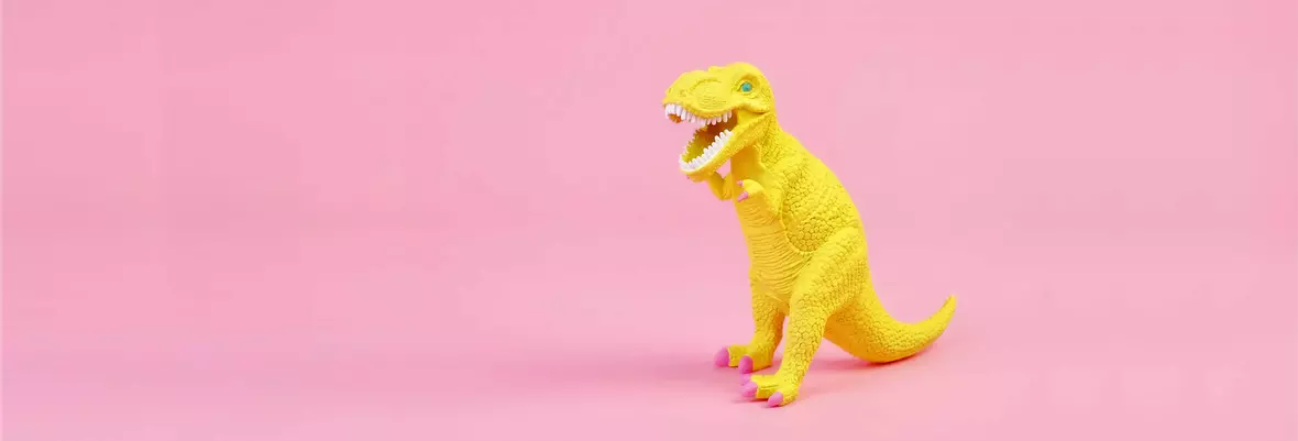 a yellow dinosaur toy on a pink background