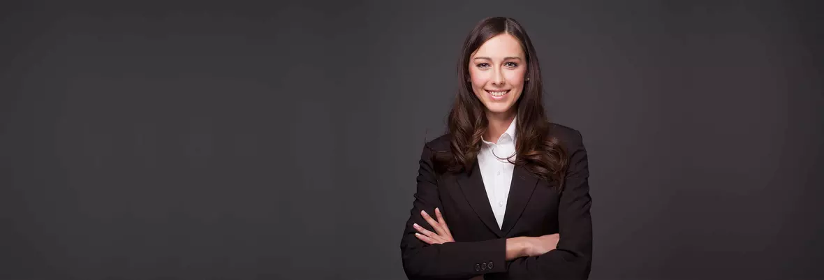 a smartly dressed woman smiling in front of a dark background