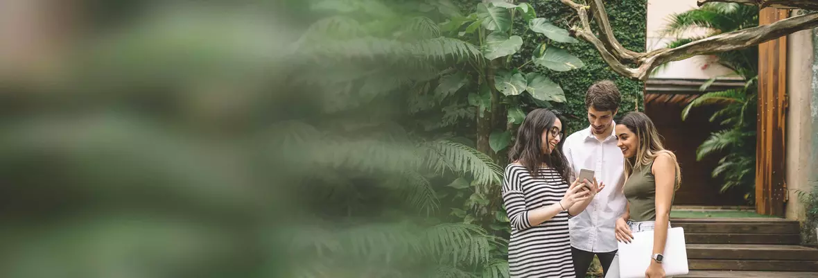 a young man and two young women looking at a mobile phone screen