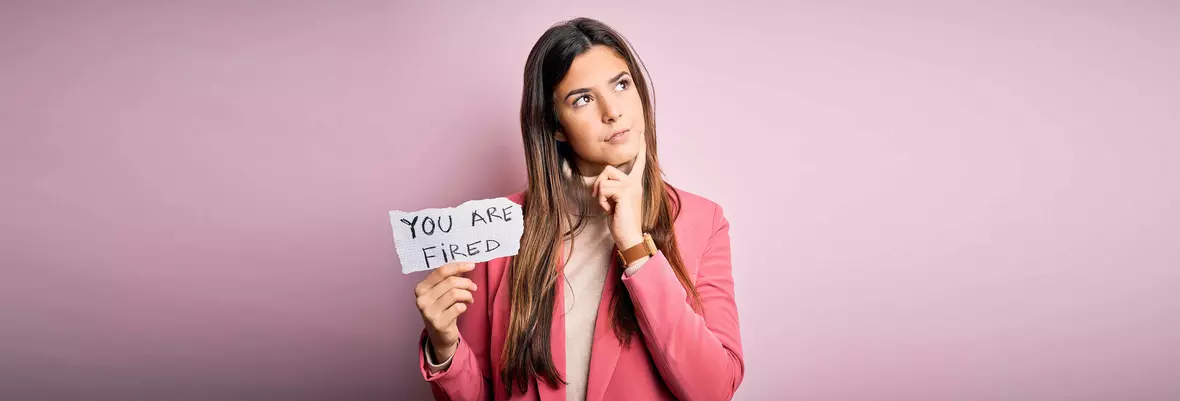 Woman in pink blazer holding paper with you are fired message