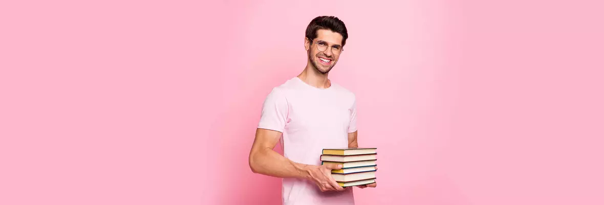 young man in glasses holding several books