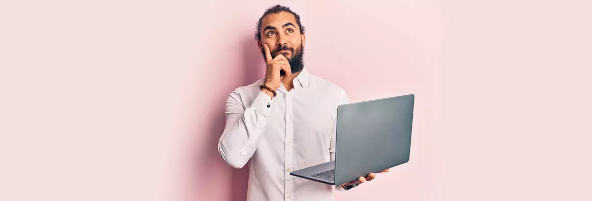 Bearded man thinking and holding a computer