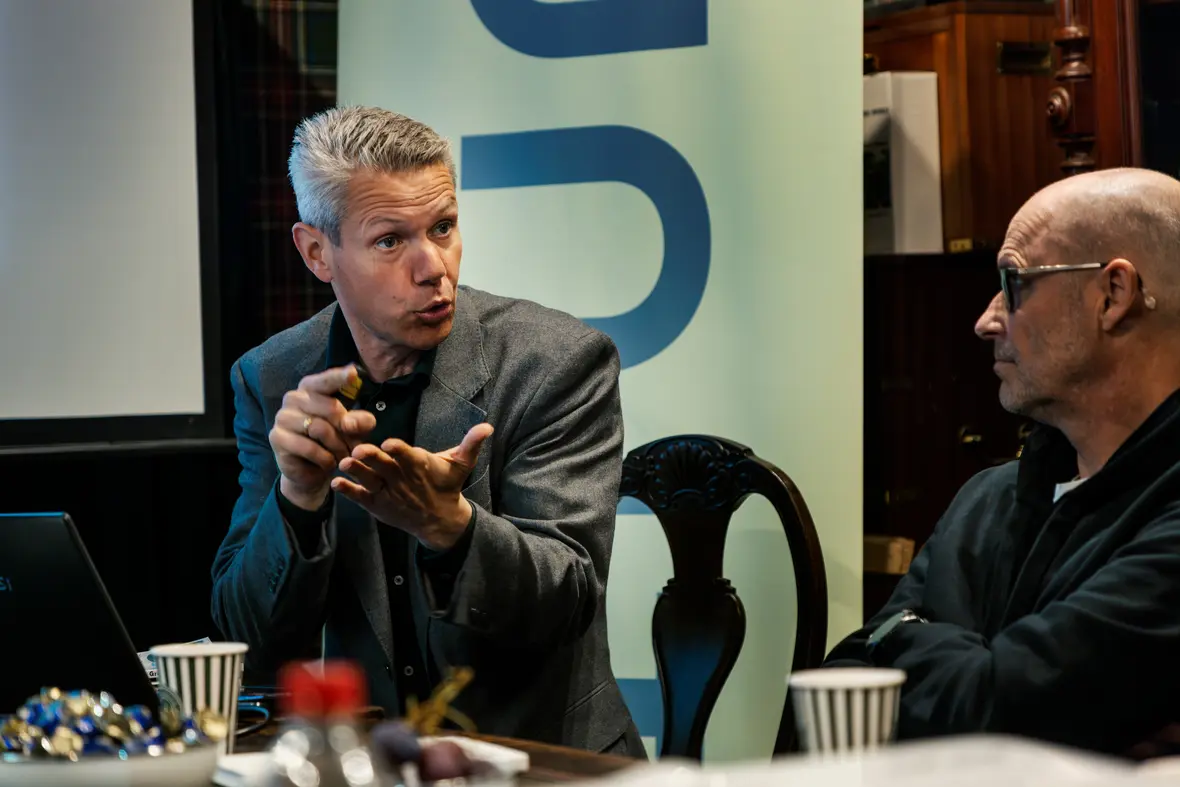 Expert speaker presenting at a Unit4 event, discussing AI and data strategies with participants during a business roundtable session.