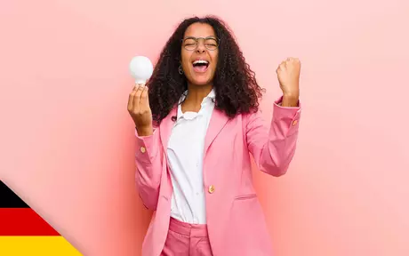 Woman shouting in celebration; holding lightbulb in one hand otehr hand clenched and half raised
