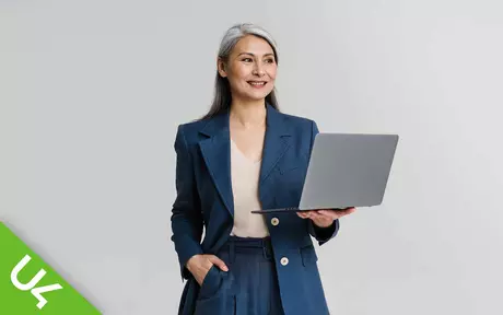 Smiling woman looking sideways to the right; one hand in pocket, other holding a laptop