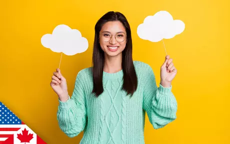 Smiling woman with both arms half raised and holding up cardboard cut-out clouds