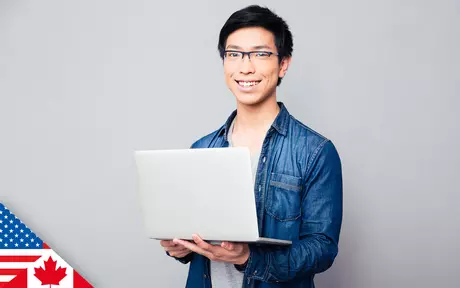 Smiling man wearing glasses, holding open laptop in both hands