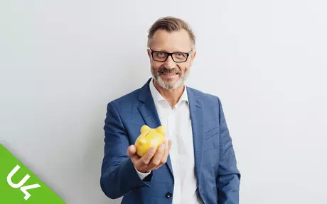 smiling man holding out small piggy bank