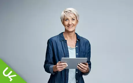 Woman smiling and holding tablet in both hands in front of her to read it