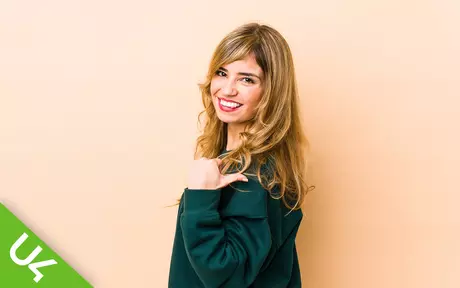 Smiling woman pointing backwards over her shoulder with her thumb