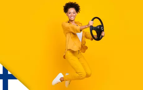 Smiling woman jumping in the air and holding a steering wheel in both hands