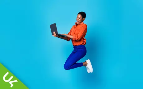Woman holding laptop jumping in the air