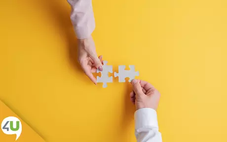 Two hands joining putting together puzzle pieces 