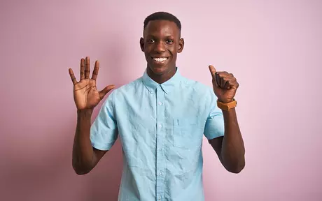 man in blue shirt holding up 6 fingers 