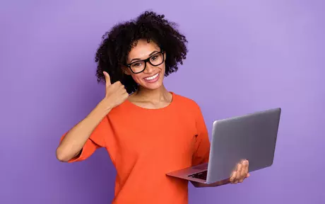 woman with glasses holding laptop with thumbs up