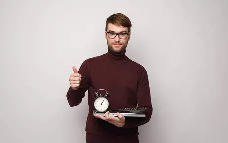 man holding notebook and clock, thumbs up