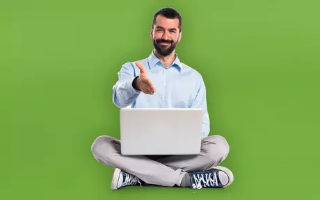 man with laptop sitting cross legged holding up 4 fingers