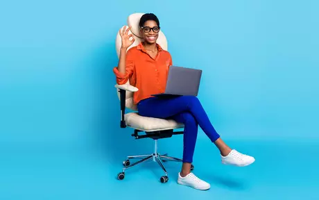 woman sitting on office chair with laptop on lap