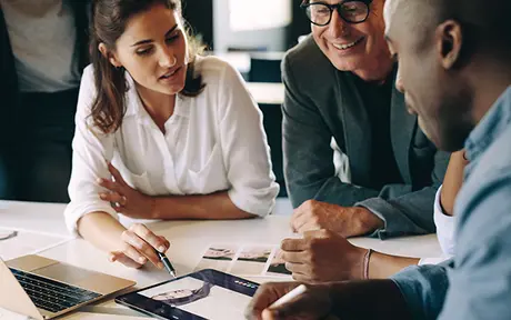 Four professionals collaborating around a white table in a modern office setting. 