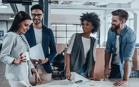 Four colleagues gathered around a table in a modern office, engaged in a collaborative discussion. 