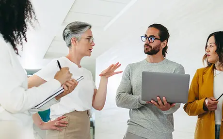 Four colleagues engage in a collaborative discussion in a modern office setting.