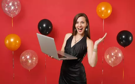 person celebrating with laptop and balloons