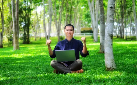 person sitting in forest with laptop