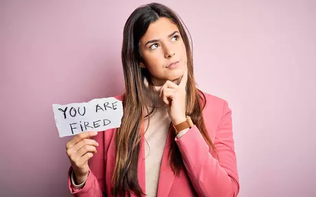 Woman in pink blazer holding paper with you are fired message
