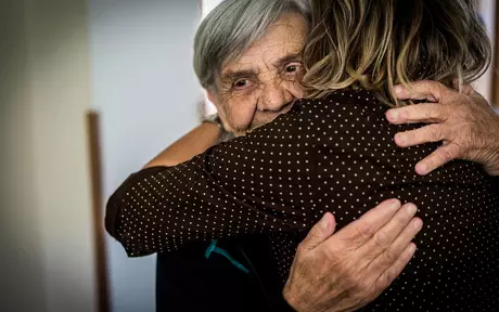 an elderly woman being hugged by a younger woman