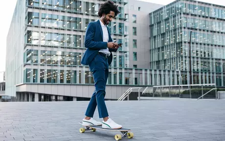 a young man texting on his phone while cruising on a skateboard