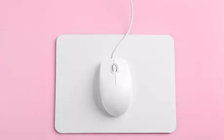 a white mouse on a white mouse mat on a pink background