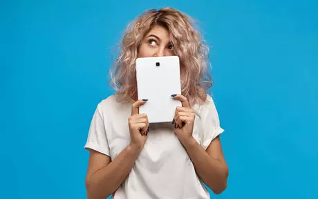 Millennial in a white t-shirt holding a tablet