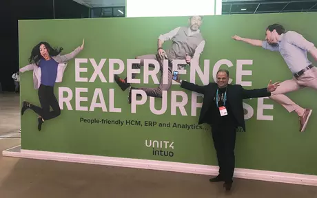 Mike Ettling stood in front of a banner that says "Experience Real Purpose"