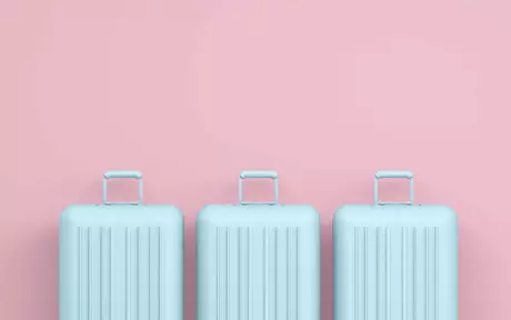 three pale blue suitcases on pink background