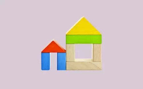Houses made of wooden blocks on pink background