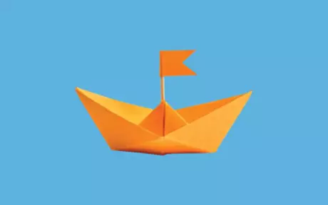 Orange paper boat on blue background
