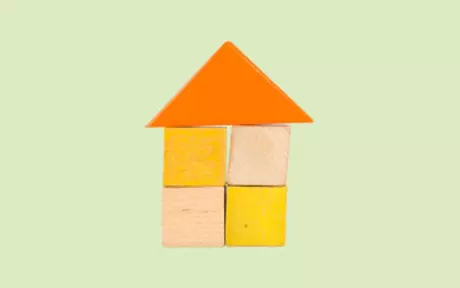 House made of wooden blocks on light green background