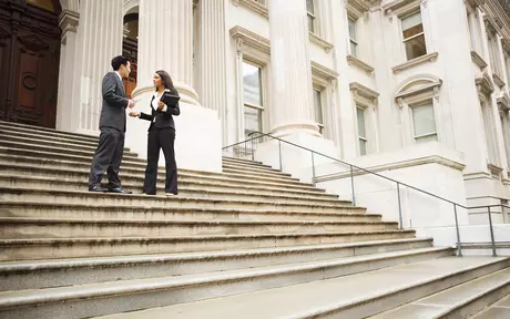 Smart dressed woman and man standing and talking on building stairs