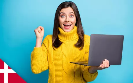 Woman holding laptop in one hand, other hand clenched in celebration